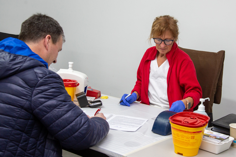 The photo shows the MAPAL employee undergoing a preliminary examination conducted by a staff member of the blood donation service.